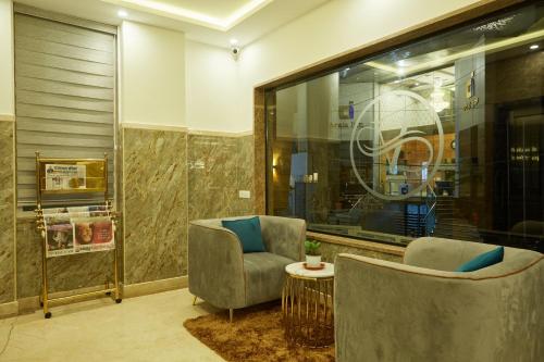 VOVO PREMIER HOTEL في بانغالور: لوبي وبه كرسيين وطاولة ونافذة