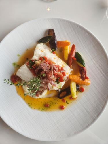 a white plate of food with meat and vegetables at Belfry & Spa by Ligne St Barth in Lourdes