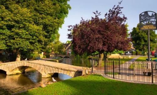 a bridge over a river in a park at Jasmine Cottage, Upper Slaughter, Cotswolds in Cheltenham