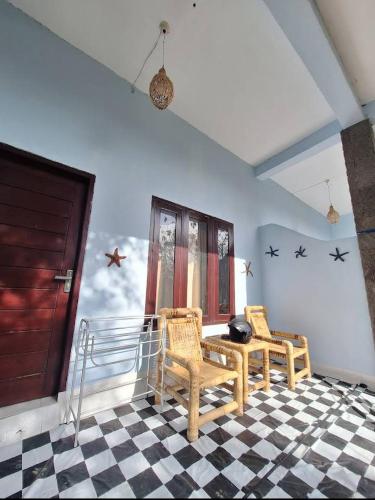 SUNRISE BUKIT ASAM HOMESTAY في كوتا لومبوك: كرسيين وطاولة في غرفة مع أرضية متقاطعة