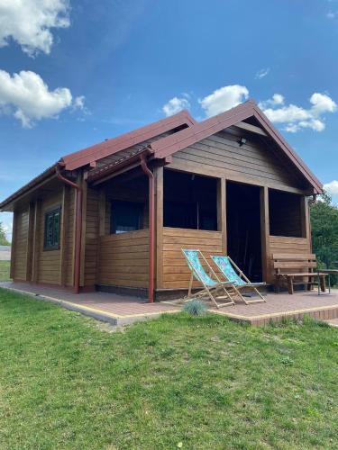 a log cabin with two chairs in front of it at Domek Letniskowy w Tumianach in Tumiany