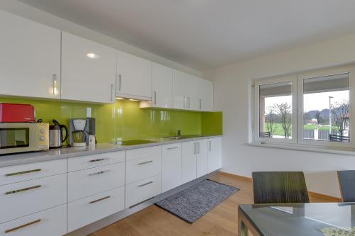 a kitchen with white cabinets and green walls at Honeycomb Chalets And Apartments Mozirje in Mozirje