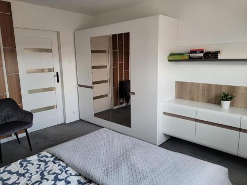 a bedroom with a bed and a mirror and a chair at Apartamenty Promyk Wisełka in Wisełka