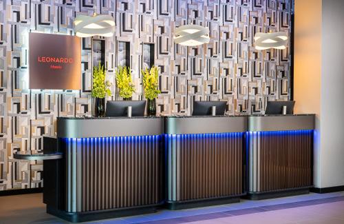 a lobby with a row of reception desks with plants at Leonardo Royal Hotel Cologne Bonn Airport in Cologne