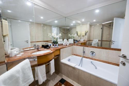 baño con bañera grande y espejo grande en David Dead Sea Resort & Spa, en Ein Bokek