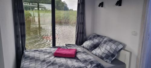 a couch in front of a window with a pink pillow at Dom na wodzie Listomie in Kruszwin
