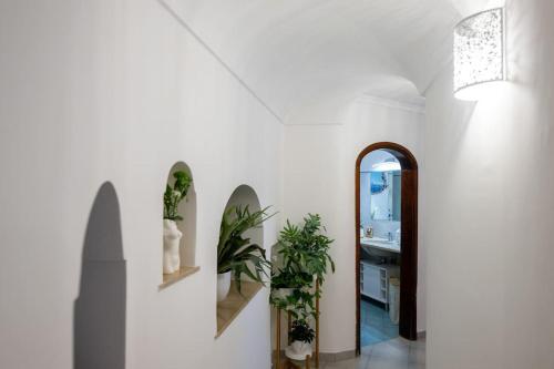 a hallway with white walls and a mirror and plants at House on the rock in Positano