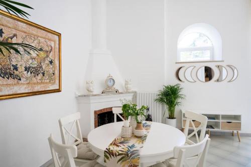 a white dining room with a white table and chairs at House on the rock in Positano