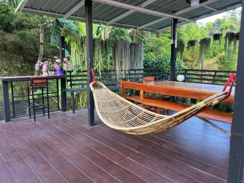 a hammock and a table and bench on a deck at Tassana House in Khao Kho