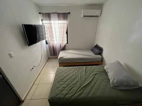 um pequeno quarto com 2 camas e uma televisão em Casa en Mazatlán em Mazatlán