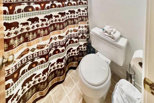 a bathroom with a toilet and a shower curtain with cows at On the Rapids - B Unit in Grand Lake