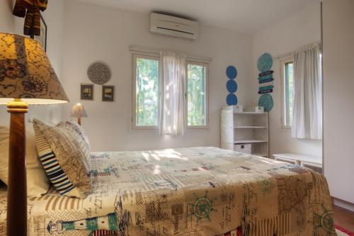 1 dormitorio con 1 cama con lámpara y ventanas en Ilha Azul House, en Ponta do Ouro