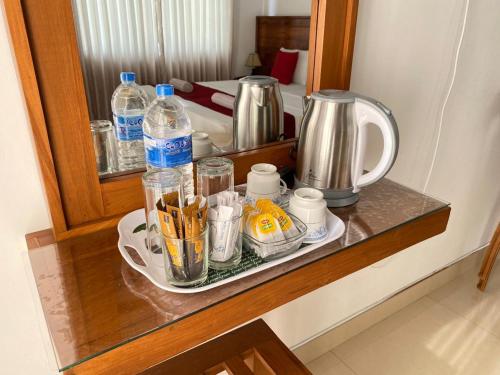 ein Regal mit Tassen und Wasserflaschen auf einem Tisch in der Unterkunft Shani Residence Kandy in Kandy