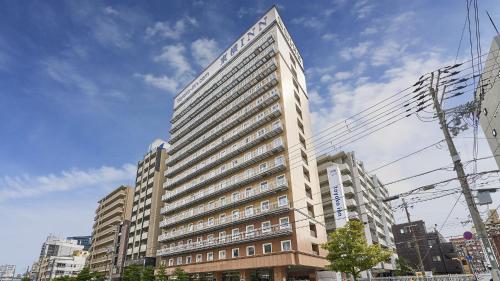 a tall building with a sign on the side of it at Toyoko Inn Osaka Tenjinbashi-suji Rokuchome in Osaka
