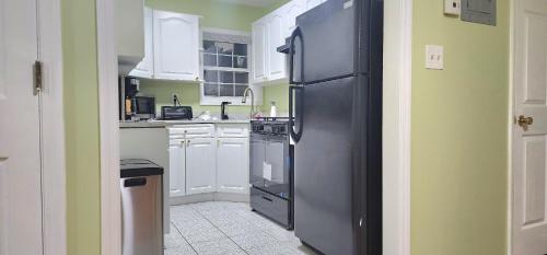 cocina con nevera negra y armarios blancos en Modern 2BR Apartment Jamaica Queens NYC, en Hillside