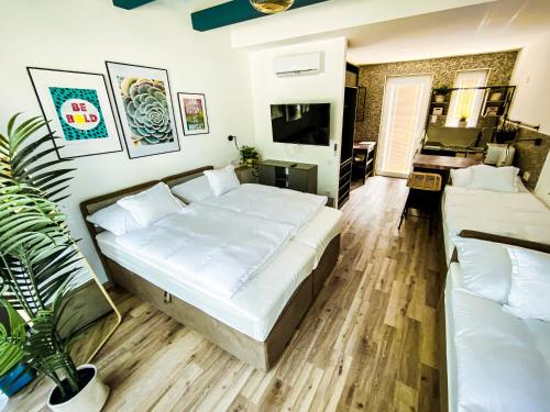 ein Schlafzimmer mit einem großen weißen Bett und einem Sofa in der Unterkunft Tisza Camping Apartmanház in Rakamaz