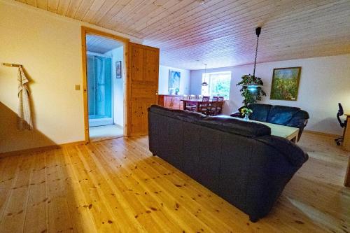 sala de estar con sofá negro y suelo de madera en Upstairs, en Saeby
