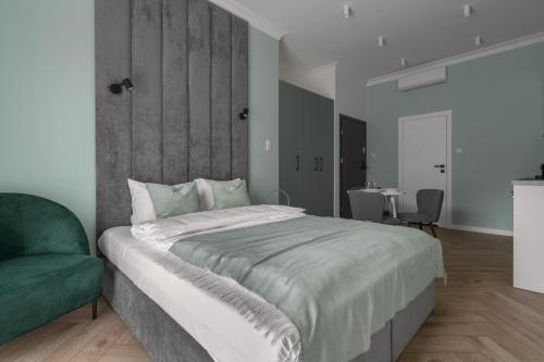a bedroom with a large bed and a green chair at APARTIO ROOMS Gliwice in Gliwice