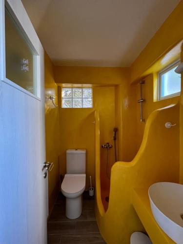 a yellow bathroom with a toilet and a sink at Seafront Villa Polyxene in Keratea