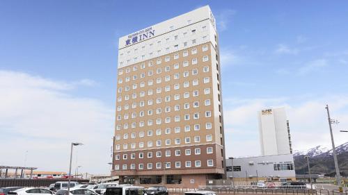 a tall building with cars parked in a parking lot at Toyoko Inn Joetsu myoko eki Nishi guchi in Joetsu