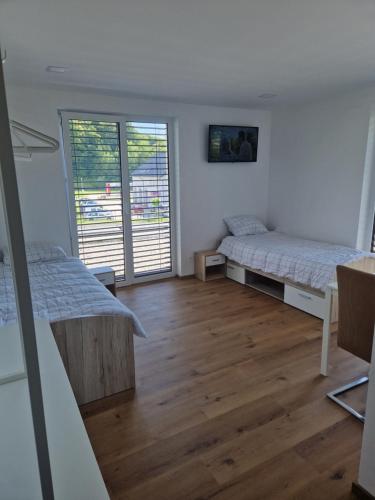 two beds in a room with wooden floors at Cona rooms in Cerkvenjak