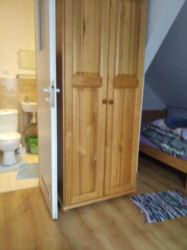 a bathroom with a toilet and a wooden door at LEŚNA OSADA in Tuchlin
