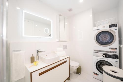 a bathroom with a sink and a washing machine at Plaza Mina Suites - Adults Recommended by Luxury Suites Cadiz in Cádiz