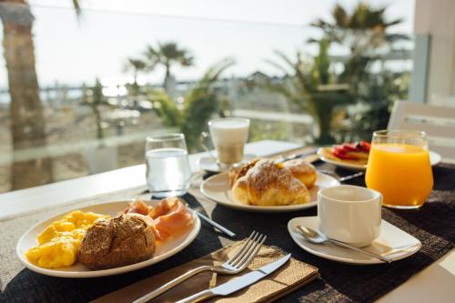a table with plates of breakfast food and orange juice at Baldinini Hotel in Rimini