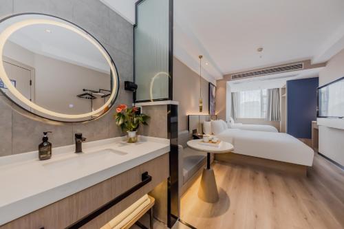 a bathroom with a sink and a mirror and a bed at Xinhuating Business Hotel in Lishui