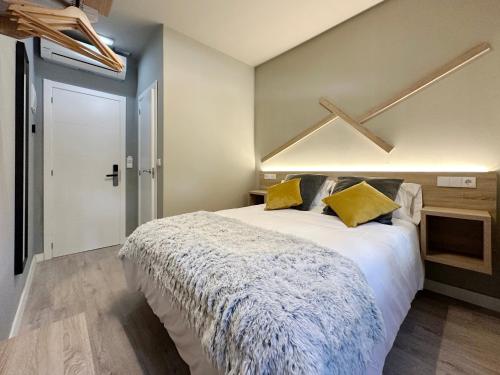 una camera da letto con un grande letto bianco con cuscini gialli di Hostal María Felisa a Candás