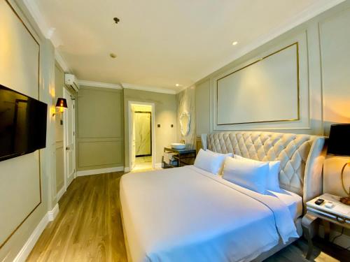 a bedroom with a large white bed and a television at Grand Eska Hotel & Suites Batam in Nagoya