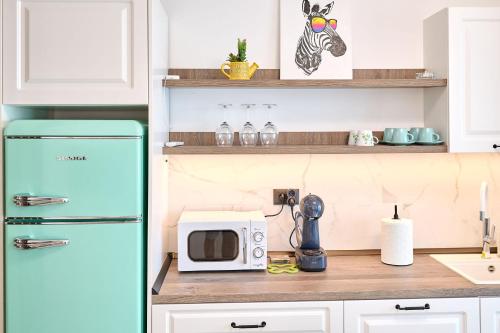 a kitchen with a refrigerator and a microwave on a counter at Beach Side Heaven Apartment in Infinity Beach Resort - parking in Mamaia