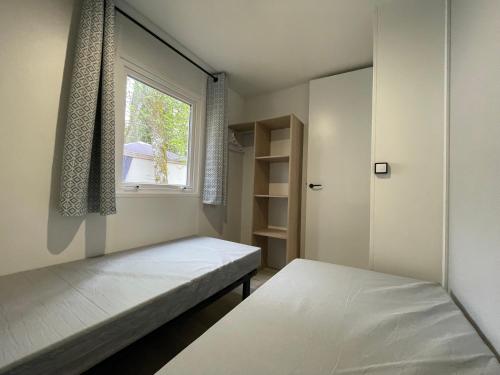 a small bedroom with two beds and a window at Camping Paradis de Maillac in Sainte-Nathalène