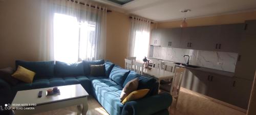 a living room with a blue couch and a kitchen at Guesthouse Isolde in Vlorë