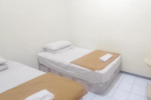 two twin beds in a room with white walls at Hotel Malang near Alun Alun Malang RedPartner in Malang