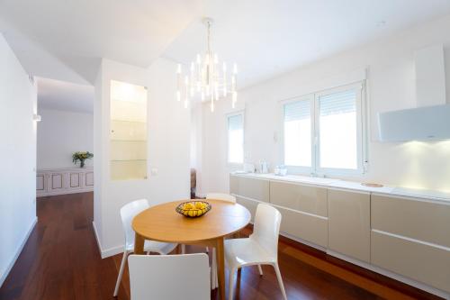a white kitchen with a wooden table and white chairs at Plaza Mina Suites - Adults Recommended by Luxury Suites Cadiz in Cádiz