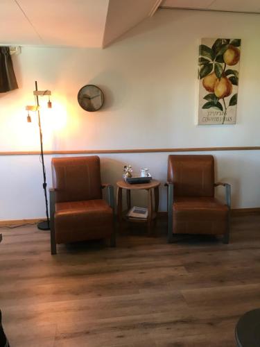 una sala de espera con 2 sillas y una cruz en la pared en Appartement, en Opheusden