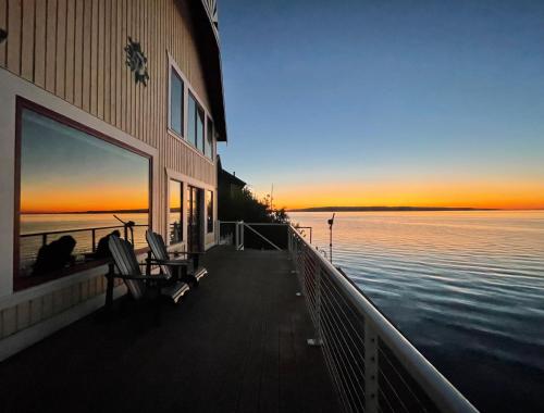 a building with a deck with a view of the water at WhidbeyBeachHouse, an Oceanfront Getaway on a Private Beach in Langley