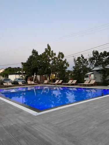a large blue swimming pool with chaise lounge chairs at Windmill Shkodra Gesthouse Camping & Grill in Shkodër