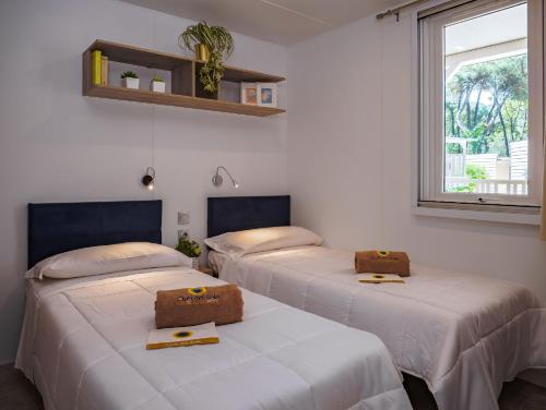 three beds in a room with a window at Club del Sole Rivaverde Easy Camping Village in Marina di Ravenna