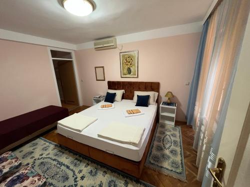 a bedroom with a bed with white sheets and blue pillows at Hostel Dino in Mostar