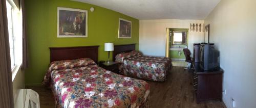a hotel room with two beds and a flat screen tv at Discovery Inn in Modesto