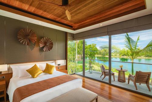 a bedroom with a bed and a large glass window at Aquella Lakeside Villas in Thai Muang