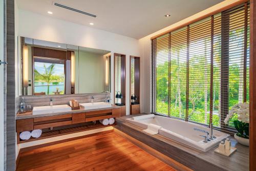 a bathroom with two sinks and a tub and a large window at Aquella Lakeside Villas in Thai Muang