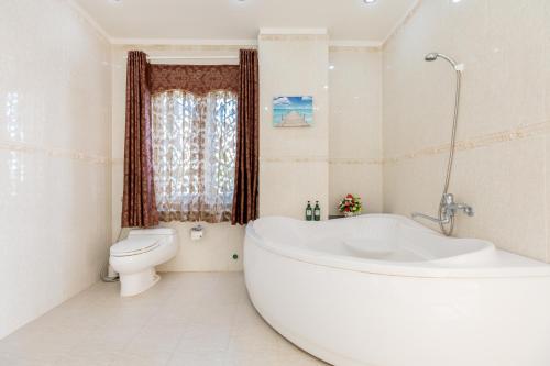 een witte badkamer met een bad en een toilet bij Palm Villa 22 - Ocean View 3bedrooms in Vung Tau