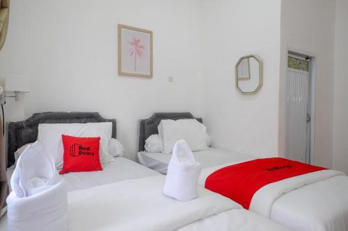 two white beds with red pillows in a room at RedDoorz Plus At Lovina Inn Tonrangeng River Side in Parepare