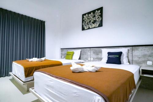 two beds in a hotel room with towels on them at Urbanview Pecatu Residence Bali by RedDoorz in Ungasan