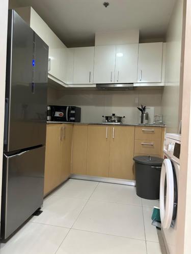 a kitchen with white cabinets and a stainless steel refrigerator at One Uptown Residence - Thompson Suites in Manila