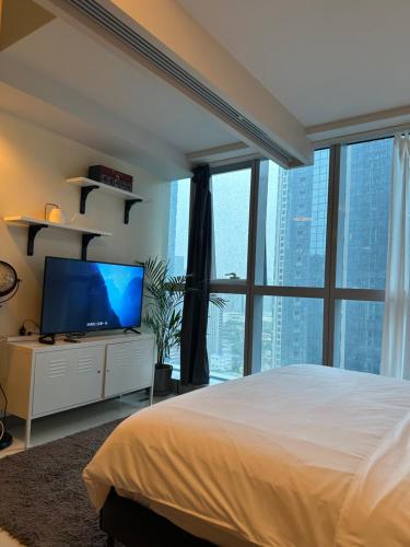 a bedroom with a bed and a large window at One Uptown Residence - Thompson Suites in Manila