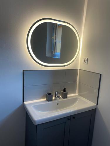 La salle de bains est pourvue d'un lavabo et d'un miroir rond. dans l'établissement Grand appartement hyper centre Grasse, à Grasse